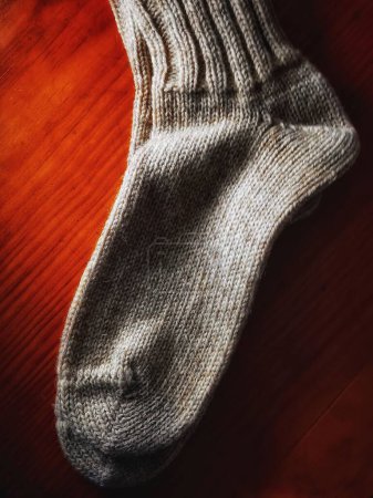 Photo for A white Warm woolen sock for cold winter on red fabric background - Royalty Free Image