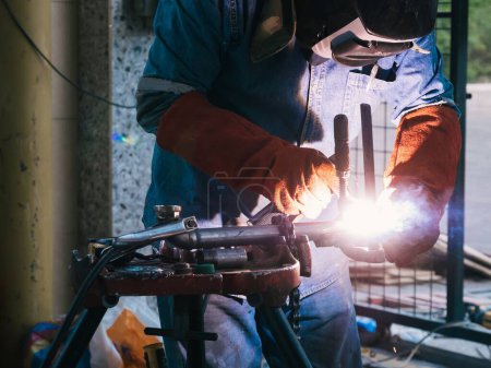 Téléchargez les photos : Un homme portant un masque soudant des mains courantes en métal - le concept de production de métal artisanal - en image libre de droit