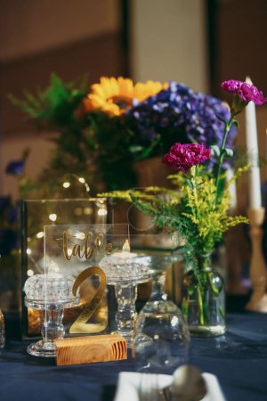 Téléchargez les photos : Une verticale d'une table de célébration avec un signe numérique décoré de fleurs, préparatifs pour une célébration - en image libre de droit