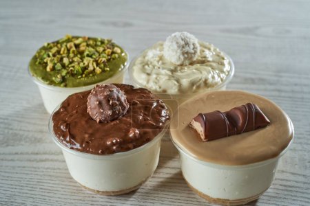 Téléchargez les photos : Les puddings en quatre tasses recouvertes de crèmes ayant des goûts différents - en image libre de droit