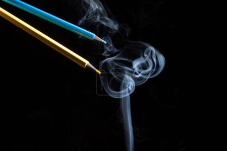 Photo for A closeup of colorful pencils and white smoke on a black background - Royalty Free Image