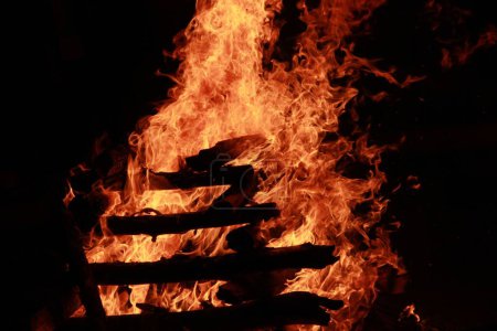 Foto de Un primer plano de una hoguera de leña ardiendo, apiladas una encima de la otra por la noche. - Imagen libre de derechos