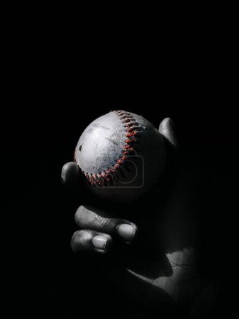Téléchargez les photos : Une main tenant une balle de baseball dans l'obscurité - en image libre de droit