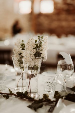 Foto de Un plano vertical de una mesa decorada con flores blancas en un vaso - Imagen libre de derechos