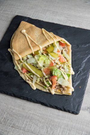 Photo for A closeup of a French crepe with meat, tomatoes, lettuce and pickles - Royalty Free Image