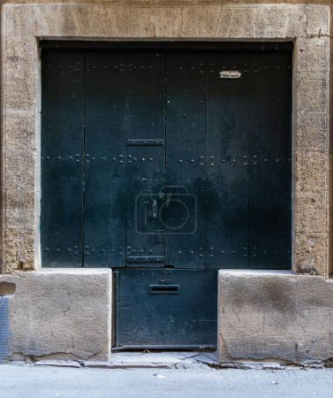 Photo for A vertical shot of an old black wooden door of a building in Portes province, France - Royalty Free Image