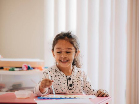 Foto de Una linda niña preescolar en la pintura casera con acuarelas en un pedazo de papel - Imagen libre de derechos