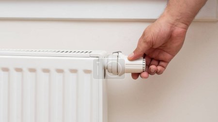 Foto de Una mano humana ajustando la temperatura de un radiador - Imagen libre de derechos