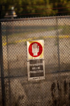 Téléchargez les photos : Un coup vertical du panneau d'avertissement sur la clôture métallique. Les intrus seront poursuivis.. - en image libre de droit
