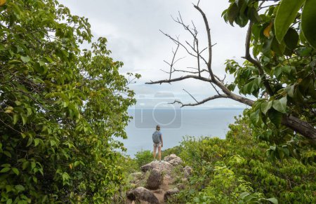 Téléchargez les photos : Femme randonneur se tient sur la falaise avec sac à dos et regarder le paysage marin à Koh Tao, Thaïlande. - en image libre de droit