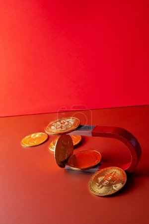 Foto de Un disparo vertical de un imán y monedas sobre un fondo rojo y naranja - Imagen libre de derechos