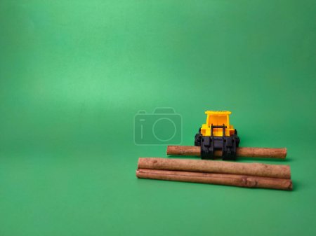 Téléchargez les photos : La pelle avec des bâtons de bois sur fond vert - le concept d'exploitation forestière illégale - en image libre de droit