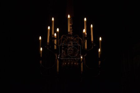 Téléchargez les photos : Un gros plan du lustre avec des bougies allumées dans l'obscurité - en image libre de droit