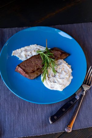 Téléchargez les photos : Un steak et purée de pommes de terre dans une assiette bleue - en image libre de droit