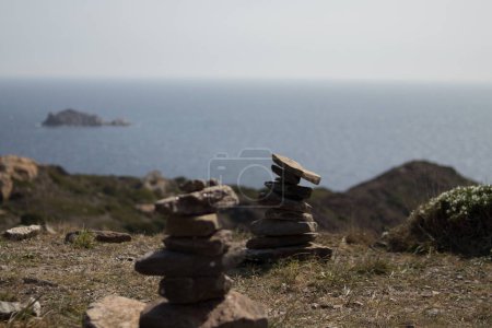 Téléchargez les photos : Un gros plan des petites piles de pierre avec une vue sur le paysage marin en arrière-plan - en image libre de droit