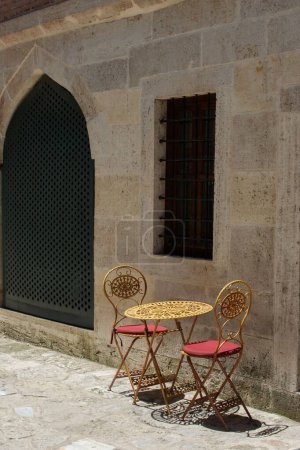 Téléchargez les photos : Plan vertical d'une table dorée avec deux chaises devant une mosquée - en image libre de droit
