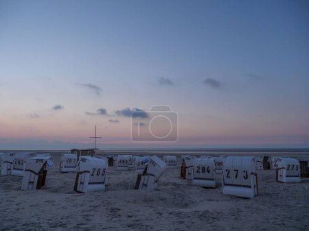 Téléchargez les photos : Un paysage de cabanes à la plage pendant le coucher du soleil à Spiekeroog, Allemagne - en image libre de droit