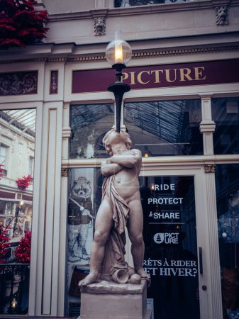 Photo for A vertical shot of a beautiful street lamp with a statue of a young boy in Nantes, France - Royalty Free Image