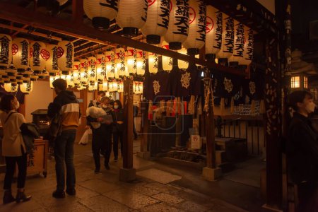 Photo for Inside of a Japanese cafe with lots of lamps hanging from the ceiling, wooden decorations and people inside - Royalty Free Image