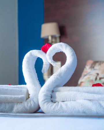 Téléchargez les photos : La vue verticale des cygnes en serviettes blanches - lit décoré pour couples - en image libre de droit