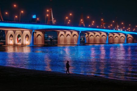 Téléchargez les photos : Une vue panoramique d'un pont au-dessus de la rivière avec des lampes éclairées la nuit - en image libre de droit