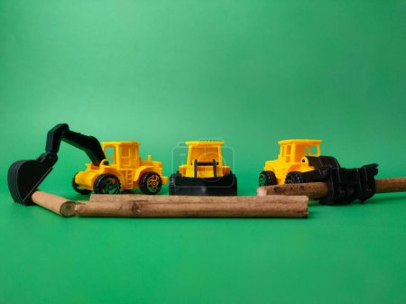 Foto de Las excavadoras con palos de madera sobre un fondo verde - el concepto de tala ilegal - Imagen libre de derechos