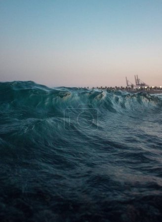 Téléchargez les photos : Une longue exposition verticale de vagues bleues recouvrant la scène portuaire à un coucher de soleil tranquille - en image libre de droit