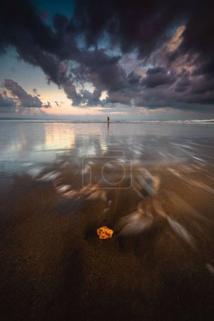 Foto de Una hermosa vista vertical de una hembra de pie en medio de una orilla con una larga exposición al amanecer - Imagen libre de derechos
