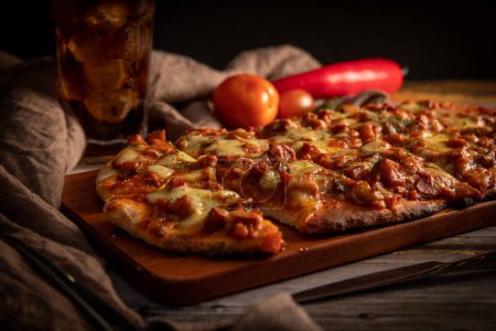 Téléchargez les photos : Un gros plan de délicieuse pizza avec des légumes en arrière-plan. - en image libre de droit