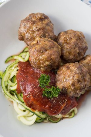 Photo for A vertical closeup shot of the meatballs with tomato sauce and zoodles on a white plate - Royalty Free Image