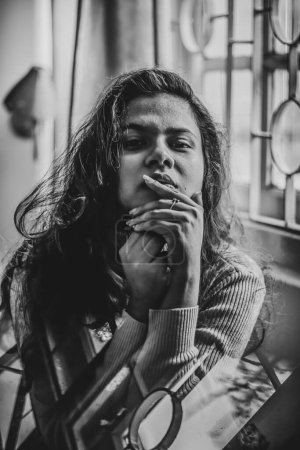 Téléchargez les photos : Un portrait en niveaux de gris d'une femme indienne attrayante assise et regardant droit - en image libre de droit