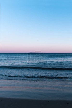 Foto de Un disparo vertical de una tranquila puesta de sol rosa sobre el mar - Imagen libre de derechos