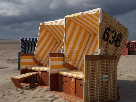 Téléchargez les photos : Les chaises longues à capuchon, sur la plage de sable de l'île Langeoog en mer du Nord, par une journée nuageuse - en image libre de droit