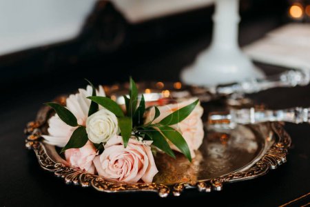 Photo for A small bouquet of wedding roses put on the plate on the blurred background during the ceremony - Royalty Free Image