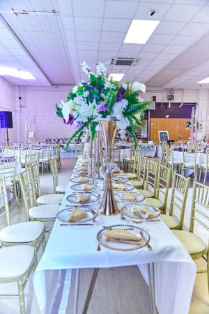 Téléchargez les photos : Une verticale de l'ustensile de tables ensemble et décoré avec des bouquets de fleurs dans une salle de mariage, lieu - en image libre de droit