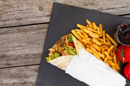 Foto de Un primer plano de shawarma con un lado de papas fritas sobre un fondo negro - Imagen libre de derechos