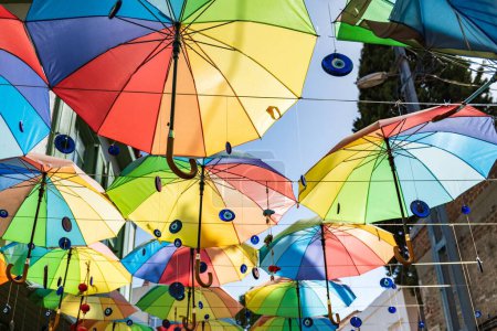 Foto de Una toma de bajo ángulo de coloridos paraguas y amuletos Nazar colgando en la calle - Imagen libre de derechos