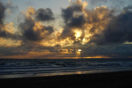 Téléchargez les photos : Un beau coucher de soleil sur la plage avec un ciel nuageux en arrière-plan - en image libre de droit