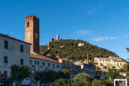 Foto de Un plano de ángulo bajo de una torre histórica y edificios en Noli a lo largo de la calle Via Aurelia, Liguria, Italia - Imagen libre de derechos
