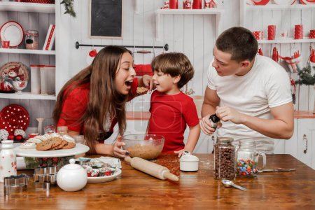Téléchargez les photos : Un beau couple caucasien avec leur enfant souriant et cuisinant dans la cuisine - en image libre de droit