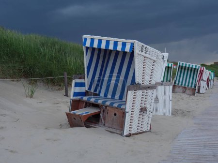 Téléchargez les photos : Les petits sièges en bois sur le bord de la mer le soir à Juist, Allemagne - en image libre de droit