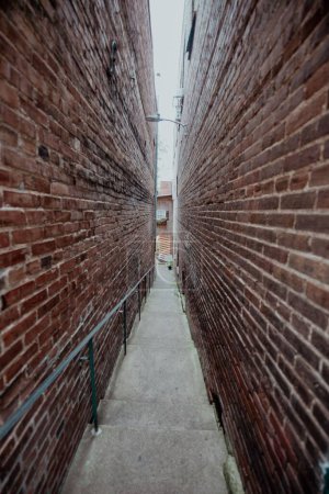 Photo for A vertical shot of a narrow stairway between brick walls. - Royalty Free Image