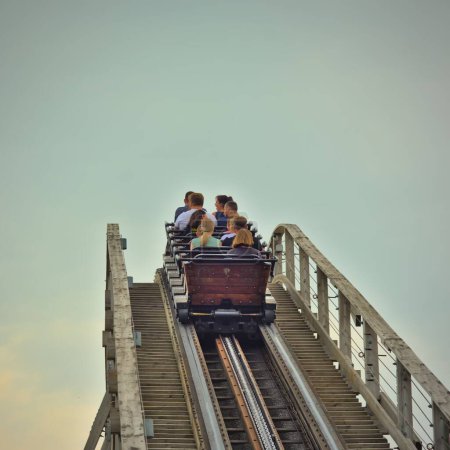 Photo for A low-angle view of people sitting on a rollercoaster as its climbs up - Royalty Free Image