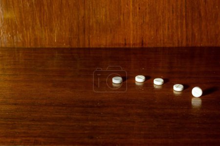 Foto de Un primer plano de píldoras blancas, y medicamentos sobre fondo marrón - Imagen libre de derechos