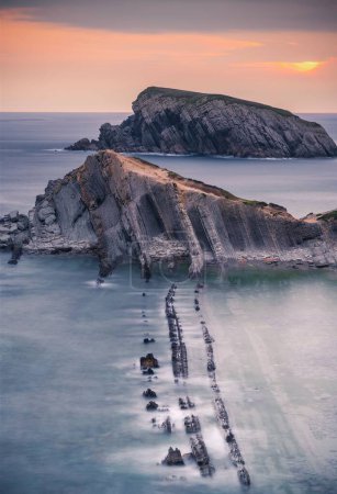 Foto de Un disparo vertical de las rocas en el mar al atardecer - Imagen libre de derechos