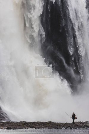 Téléchargez les photos : Vue verticale panoramique d'un homme pêchant dans la rivière près des chutes Montmorency au Québec, Canada - en image libre de droit