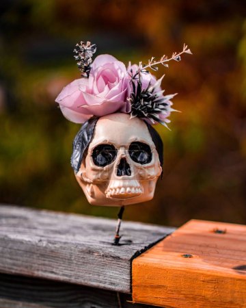 Foto de Un primer plano de una figura de cráneo con flores en un bosque - Imagen libre de derechos