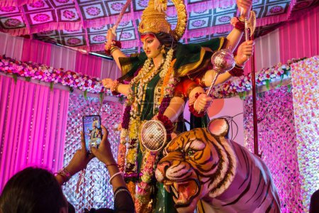 Téléchargez les photos : Une personne prenant une photo par le téléphone de l'idole de Maa Durga adoré à un Mandal à Mumbai pour Navratri - en image libre de droit