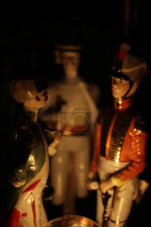 Photo for Three Napoleonic-era soldier porcelain figurines arranged as if they were lit up by a campfire - Royalty Free Image
