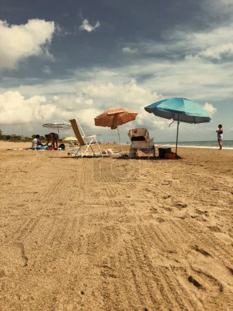 Foto de Un plano vertical de personas descansando en una playa de arena en Gava Cataluña con sillas y sombrillas - Imagen libre de derechos